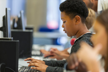 Focused junior high boy student using computer in computer lab