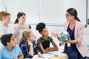 Attentive junior high school students watching geography teacher globe