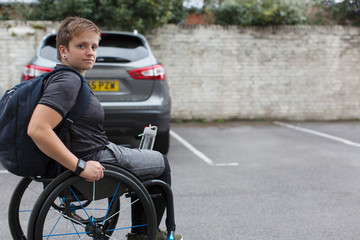 Portrait confident young female university student in wheelchair in parking lot