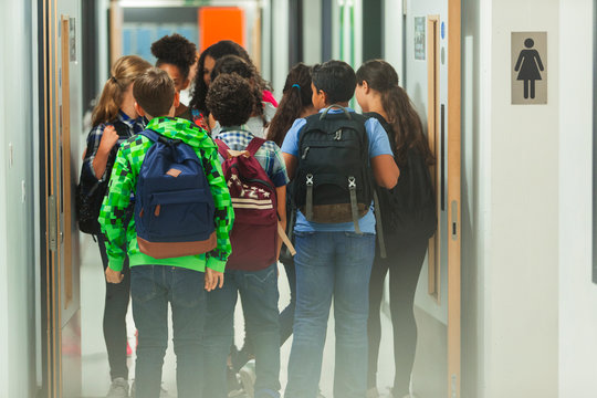 Junior high students with backpacks walking in school corridor - Powered by Adobe