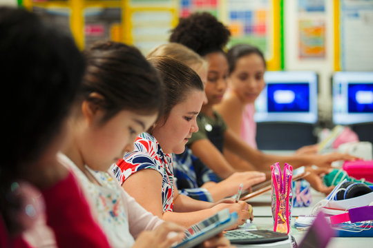Junior high school girl students studying at desk in classroom