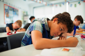 Focused junior high school boy doing homework in classroom