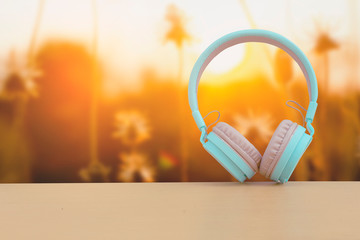 Headphones on a wooden table with a grass field with golden light.