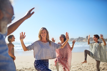 Group dancing on sunny beach during yoga retreat