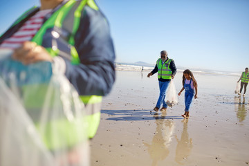 Grandfather granddaughter volunteers cleaning up litter on sunny wet sbeach