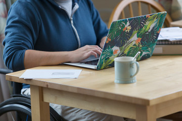 Young woman in wheelchair using laptop at table