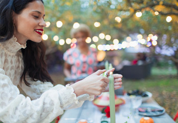 Woman lighting candles for dinner garden party