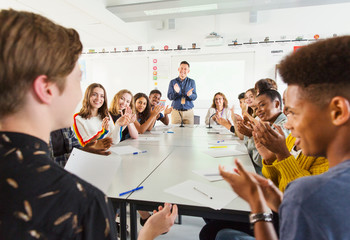 High school students and teacher clapping for student in debate class