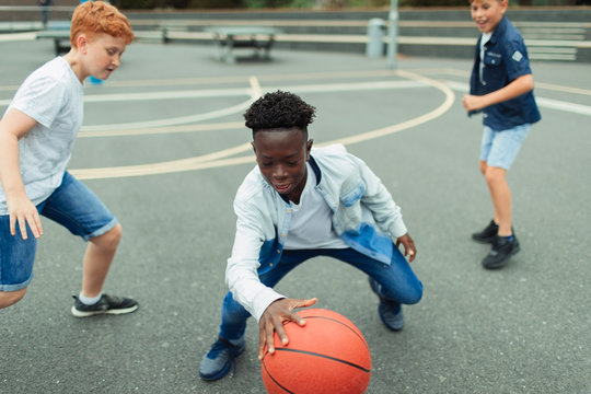 Tween boys playing basketball in schoolyard
