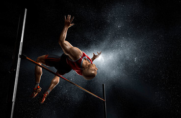 Male track and field athlete high jumping