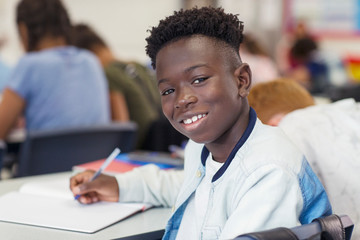 Portrait confident junior high school boy studying in classroom