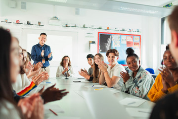 High school students and teacher clapping debate class