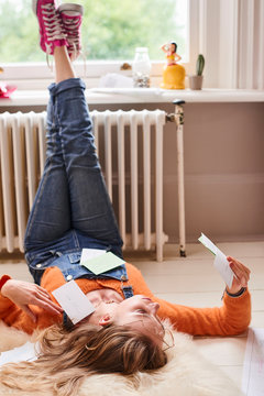Young female college student studying with flash cards on floor