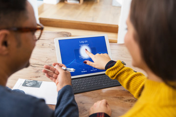 Couple paying bills online, using fingerprint log on at digital tablet
