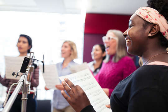 Womens choir with sheet music singing in music recording studio