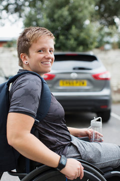 Portrait confident young female university student in wheelchair in parking lot