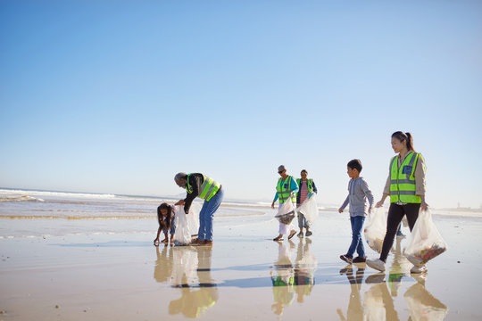Volunteers cleaning litter from wet sand beach
