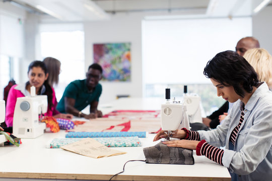 Fashion design students working at sewing machines in studio