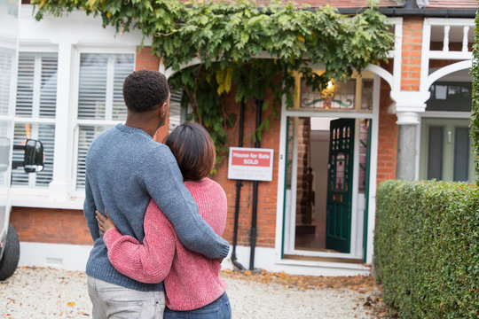 Happy, affectionate couple hugging outside new house