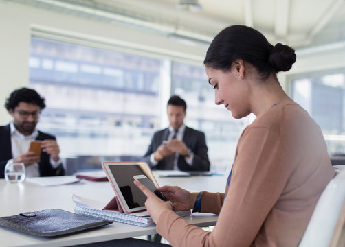 Businesswoman using smart phone in conference room meeting