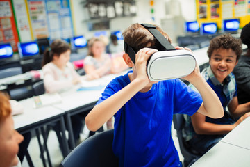 Junior high school boy student using virtual reality simulator glasses in classroom