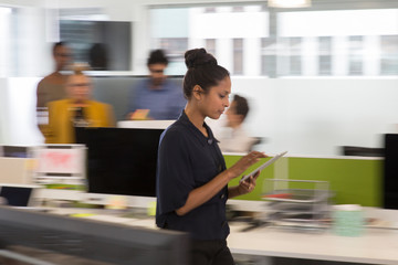 Businesswoman with digital tablet walking in office