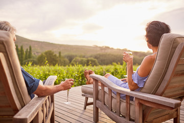 Couple relaxing, drinking champagne on lounge chairs on sunny resort patio