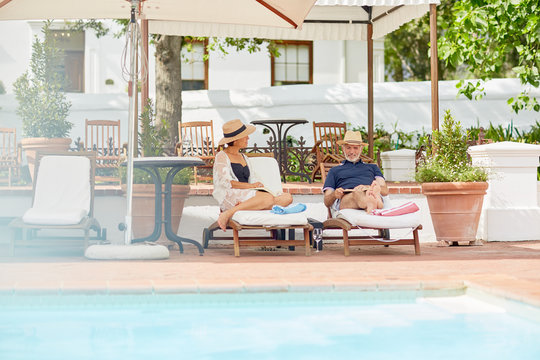 Mature couple relaxing on lounge chairs at resort poolside