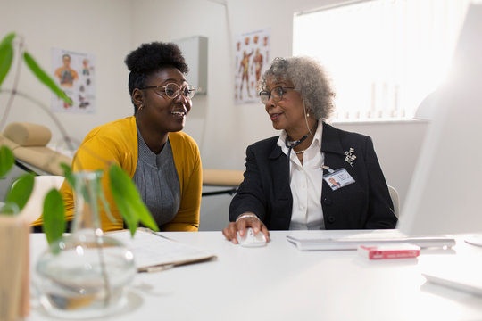 Female doctor meeting with patient at computer in doctors office