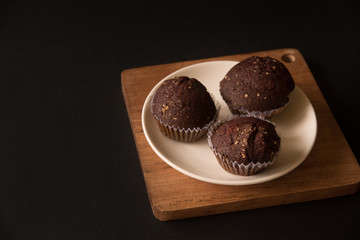 Sweet cupcaks with on dark black background. Chocolate muffins in white paper cups. Party food concept.