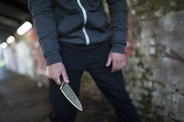Young man holding knife weapon in tunnel