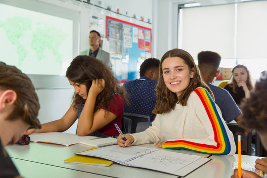 Portrait confident high school girl student taking notes during geography lesson in classroom