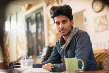Portrait confident young male college student studying in cafe