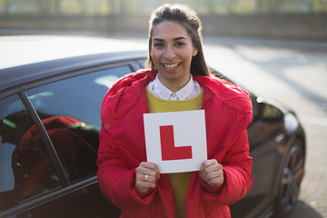 Portrait confident, happy young woman holding learners permit by car