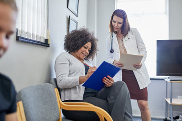 Female doctor and patient discussing paperwork in clinic waiting room