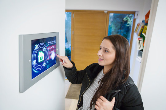 Woman leaving house, setting smart home alarm