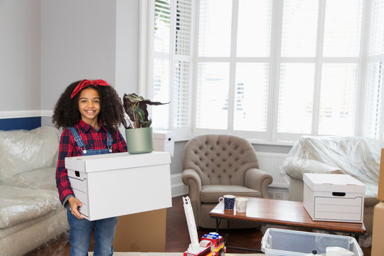 Portrait smiling, confident girl moving house, carrying cardboard box