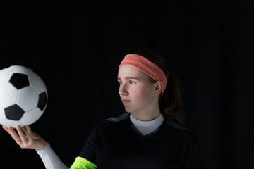 Focused teenage girl soccer player holding ball