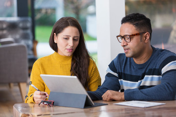 Couple paying bills at digital tablet
