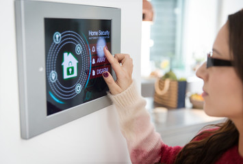 Woman setting touch screen home alarm system
