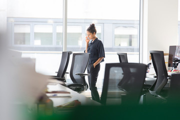 Businesswoman talking on smart phone at office window
