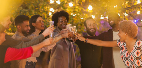 Friends celebrating, toasting champagne at dinner garden party
