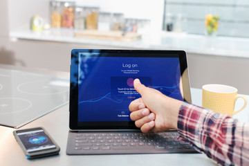 Personal perspective man logging on to digital tablet with fingerprint in kitchen