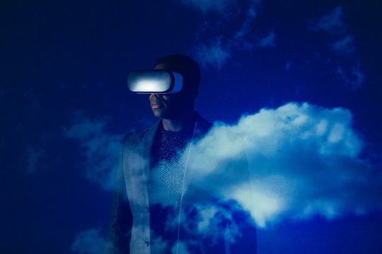 Double exposure businessman with virtual reality simulator glasses against blue sky with clouds