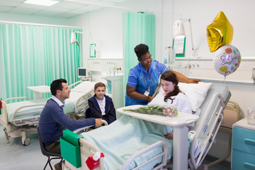 Nurse adjusting pillows for patient in hospital ward