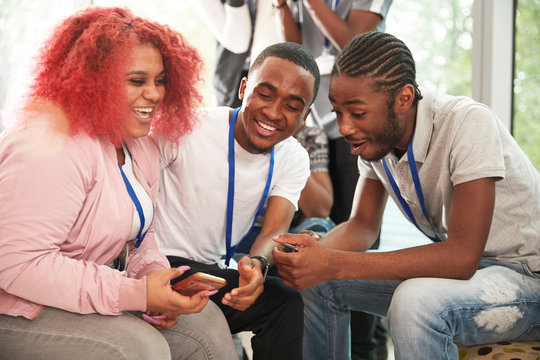Happy high school students using smart phone