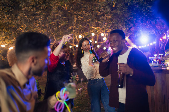 Friends dancing and singing karaoke at garden party