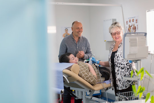 Technician performing ultrasound for happy pregnant couple in examination room