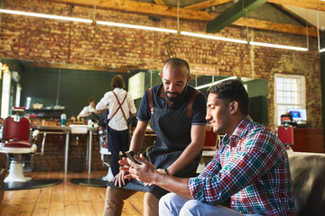 Male barber and customer with digital tablet in barbershop