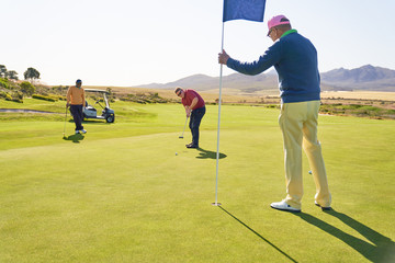 Men on sunny golf putting green